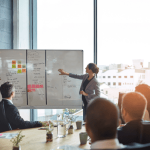 A facilitator talking a seated team through a plan mapped out on a whiteboard