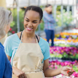 A shop worker in an apron listening warmly and attentively to an older customer